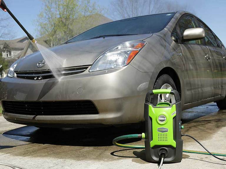 Greenworks pressure washer cleaning a car.
