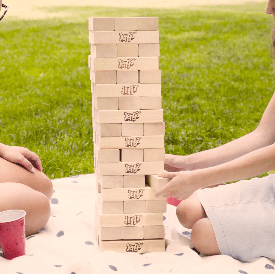 A group of people playing creative popular picnic games like Giant Jenga