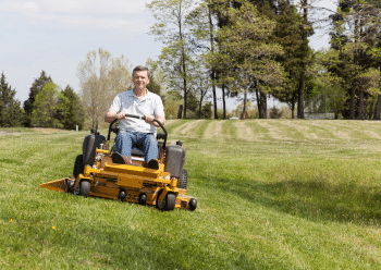A man mowing a hilly lawn with a lawn tractor