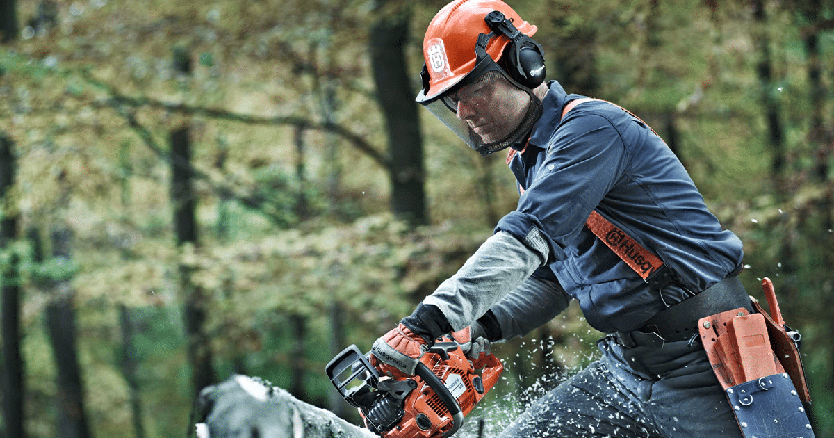Man using chainsaw with safety gear
